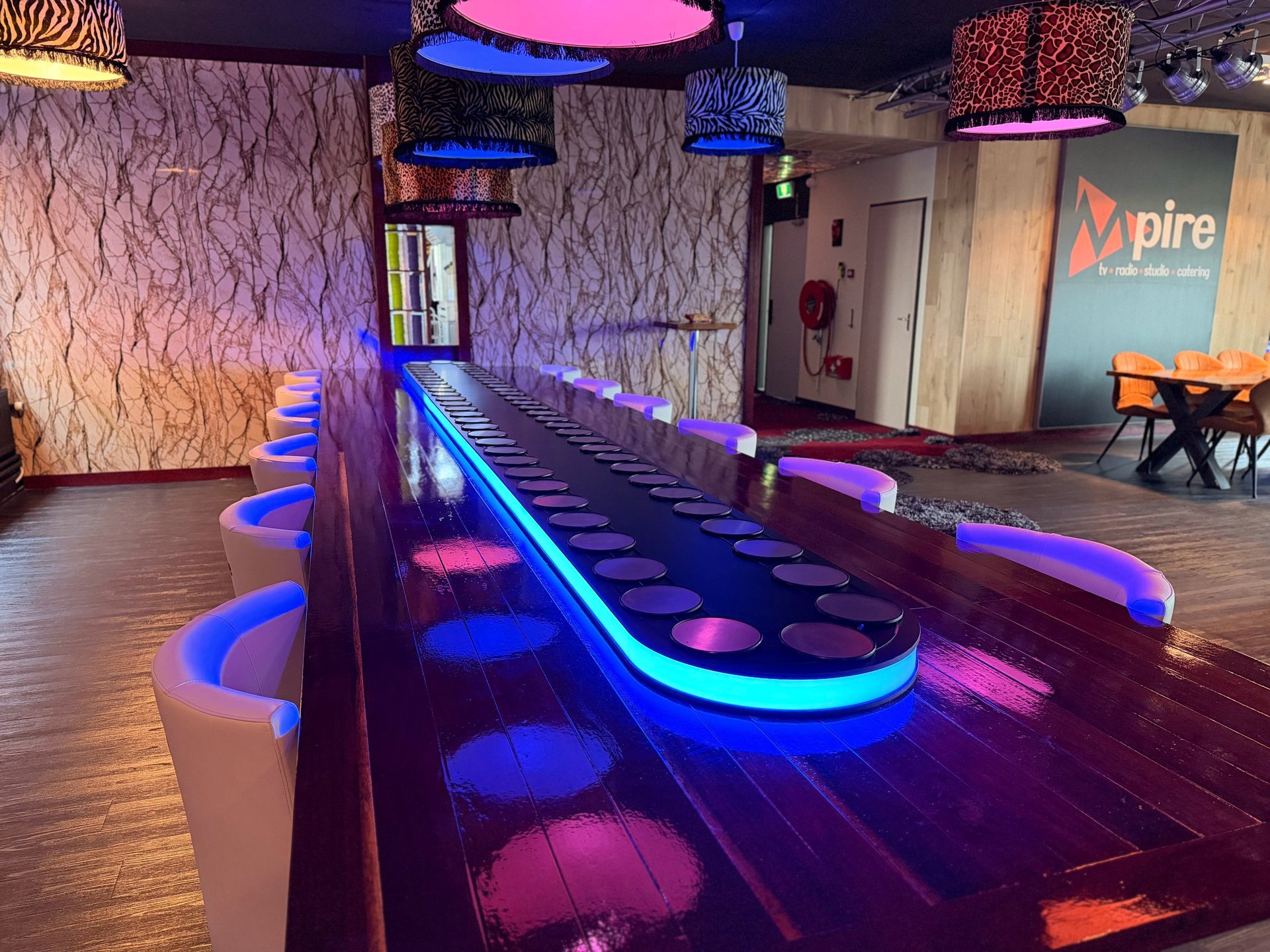 Modern bowling alley with neon blue and pink lighting, featuring illuminated lanes and colorful bumpers along the sides